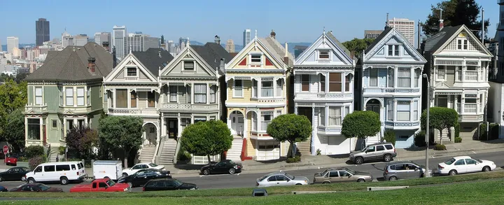 Alamo Square 对面 Steiner 街的一排维多利亚彩绘女士小楼,背后是旧金山市中心的高楼天际线