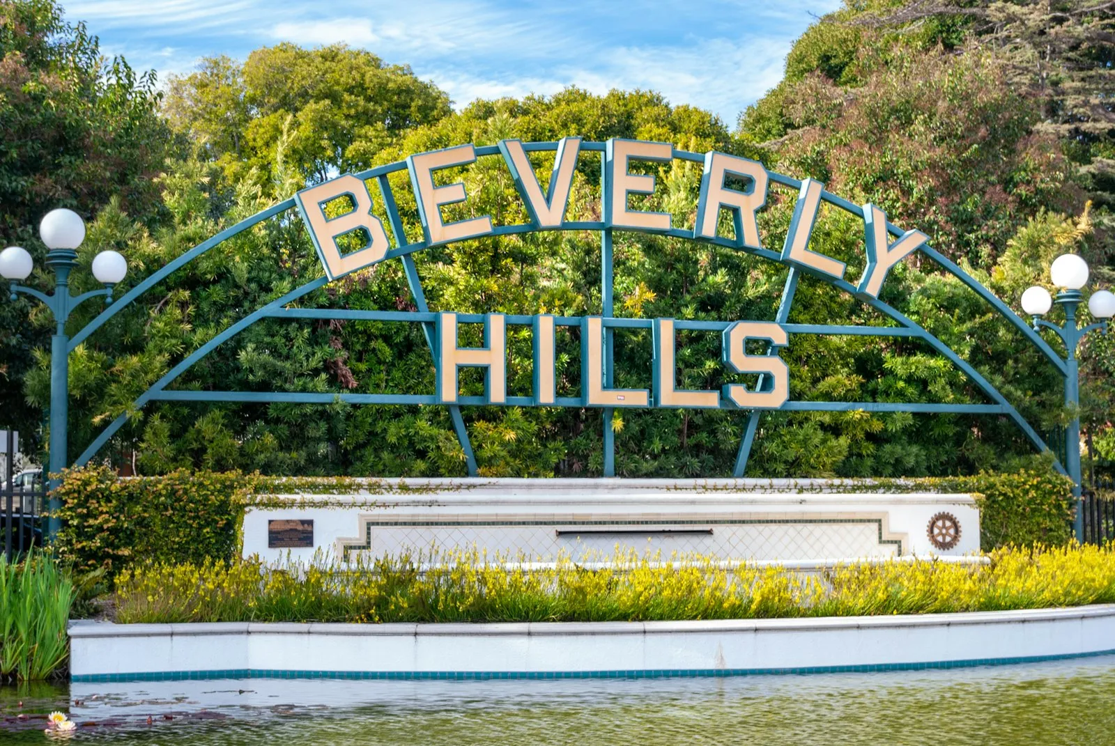 睡莲池后绿色铁架上的 Beverly Hills 招牌,两侧是圆形路灯
