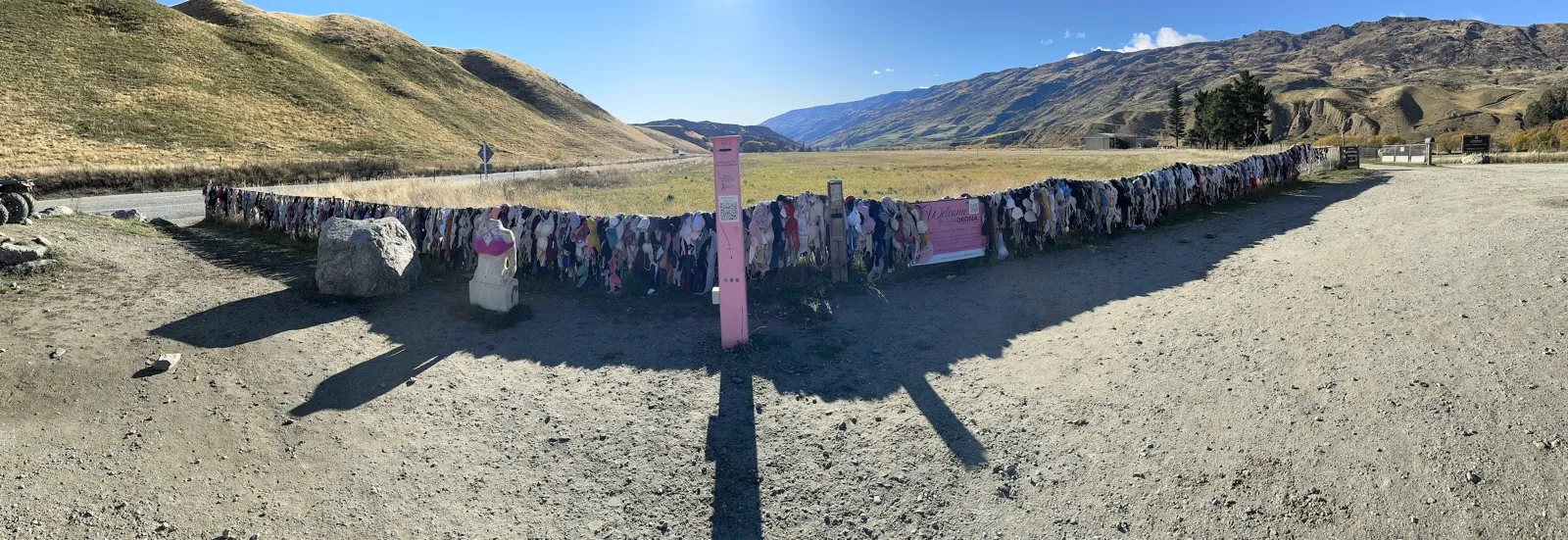 新西兰公路边著名的胸衣墙,一排彩色胸衣挂在铁丝网上,背后是蓝天与群山草原
