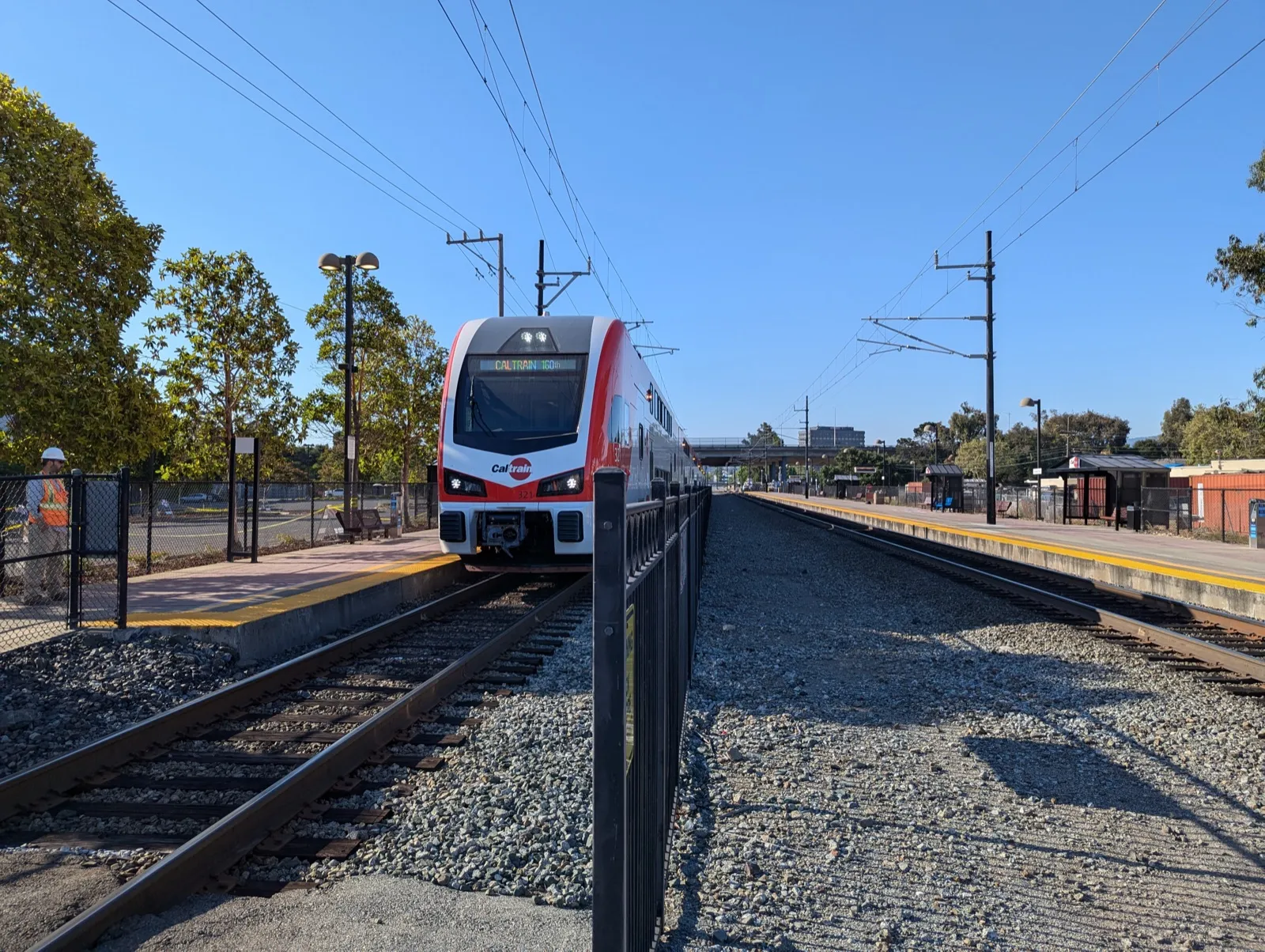 红白涂装的 Caltrain Stadler 电动列车停靠在站台边，头顶是接触网