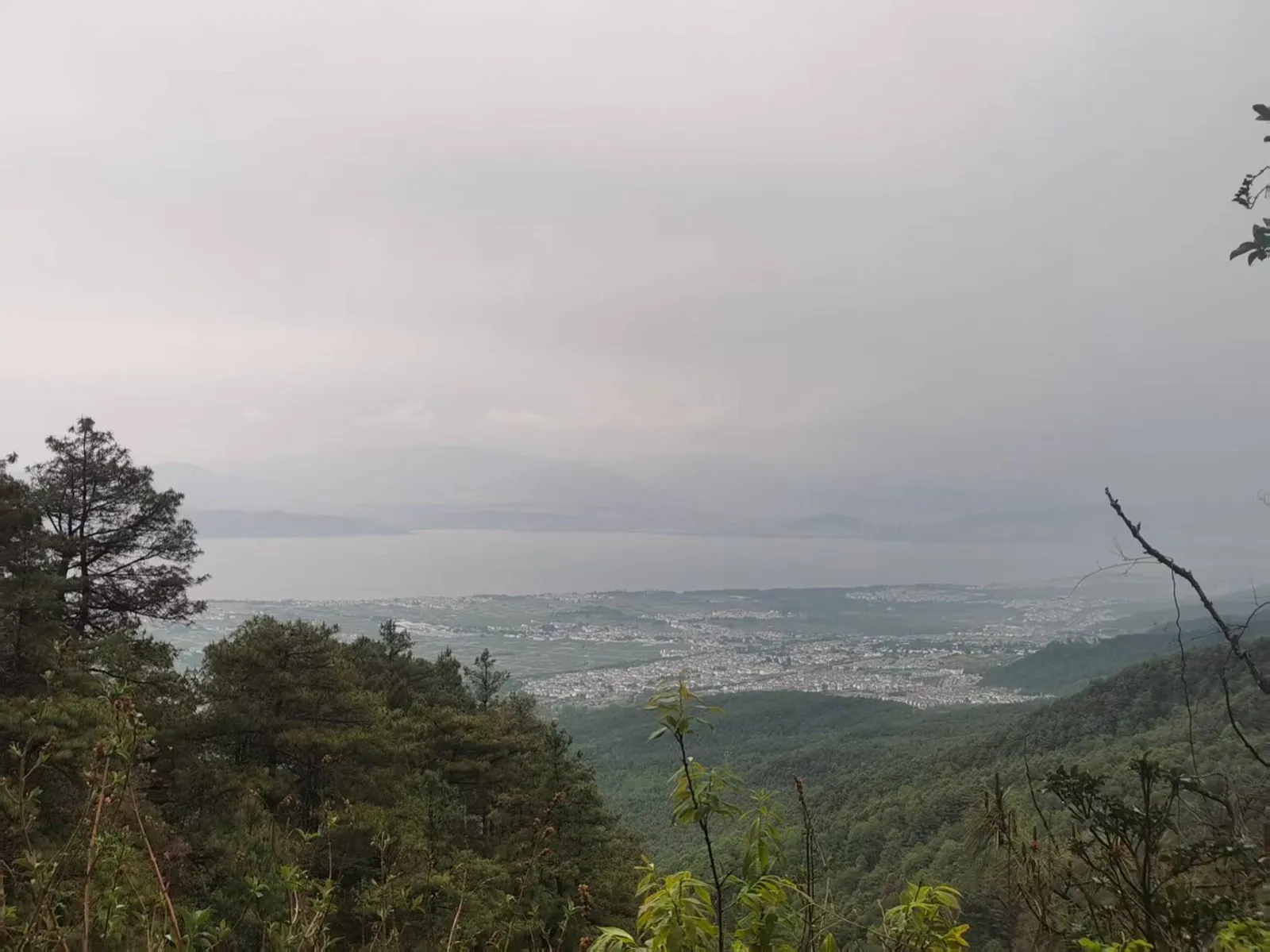 苍山玉带路上远眺，苍翠山林之下大理坝子铺展，远处一线洱海隐在薄雾里