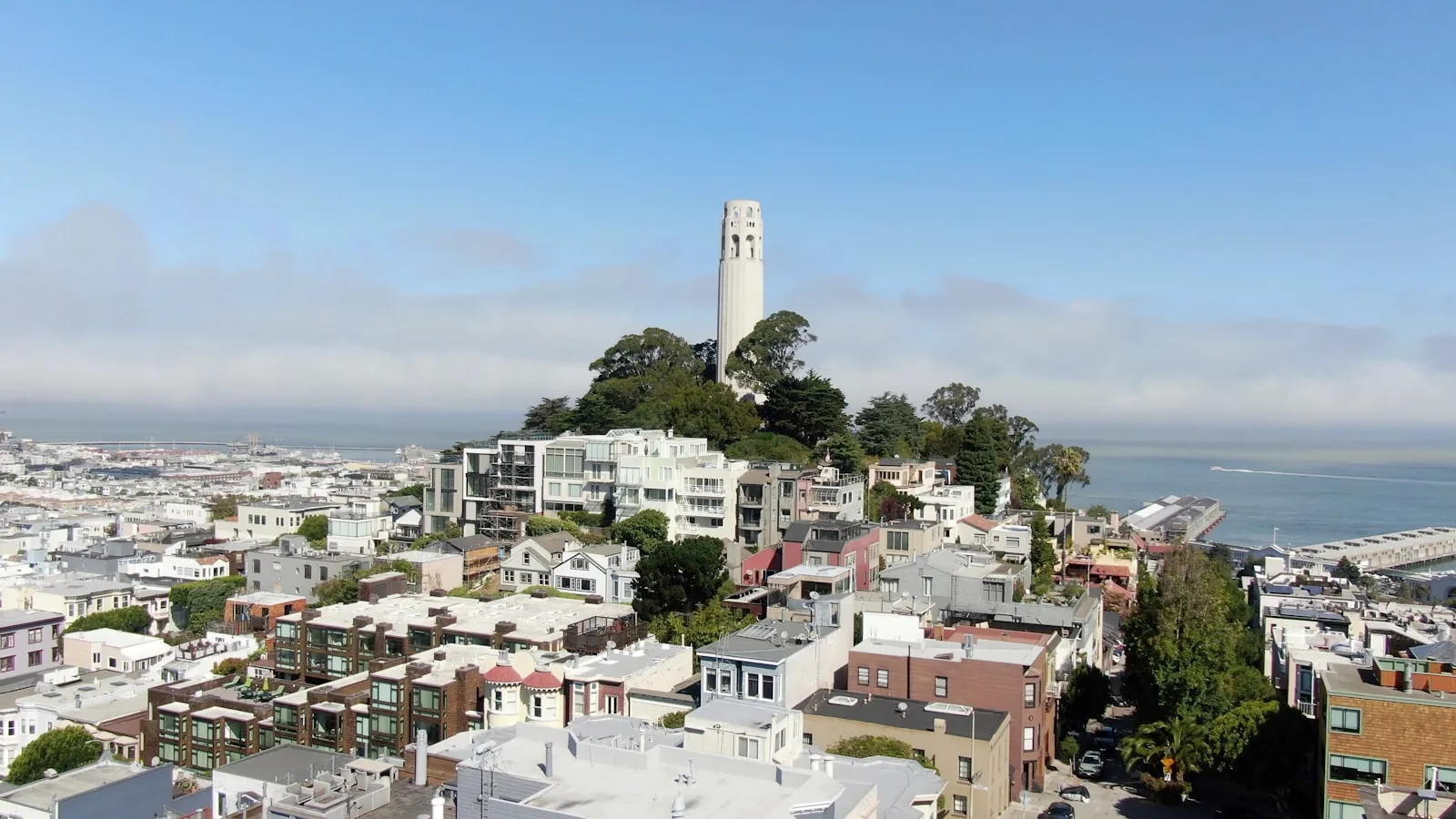 航拍电报山上的 Coit Tower 白塔、North Beach 的屋顶与海湾上的一层低雾