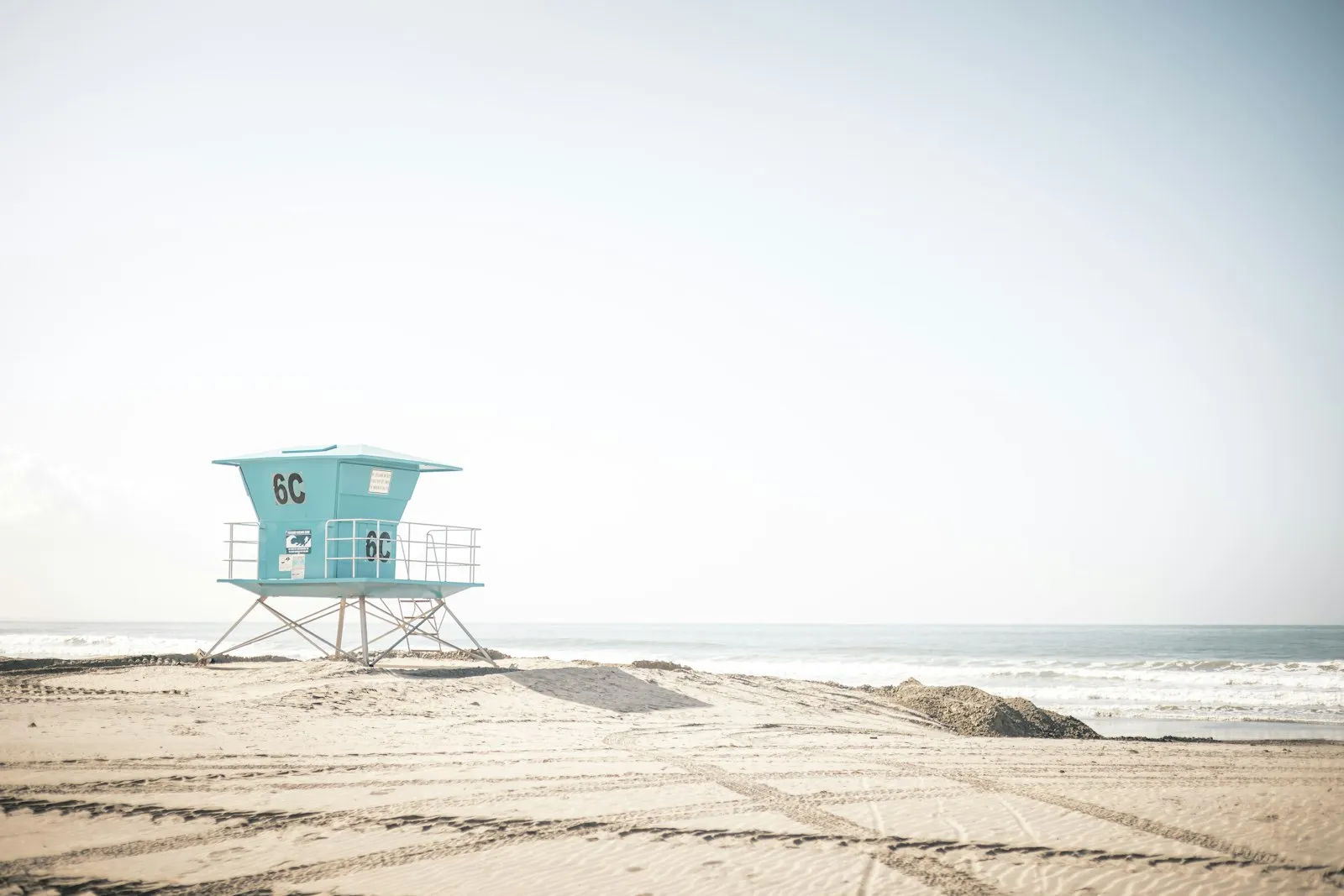 Coronado Beach 空旷的浅色沙滩上一座蓝色救生员塔,远处是平静的海面