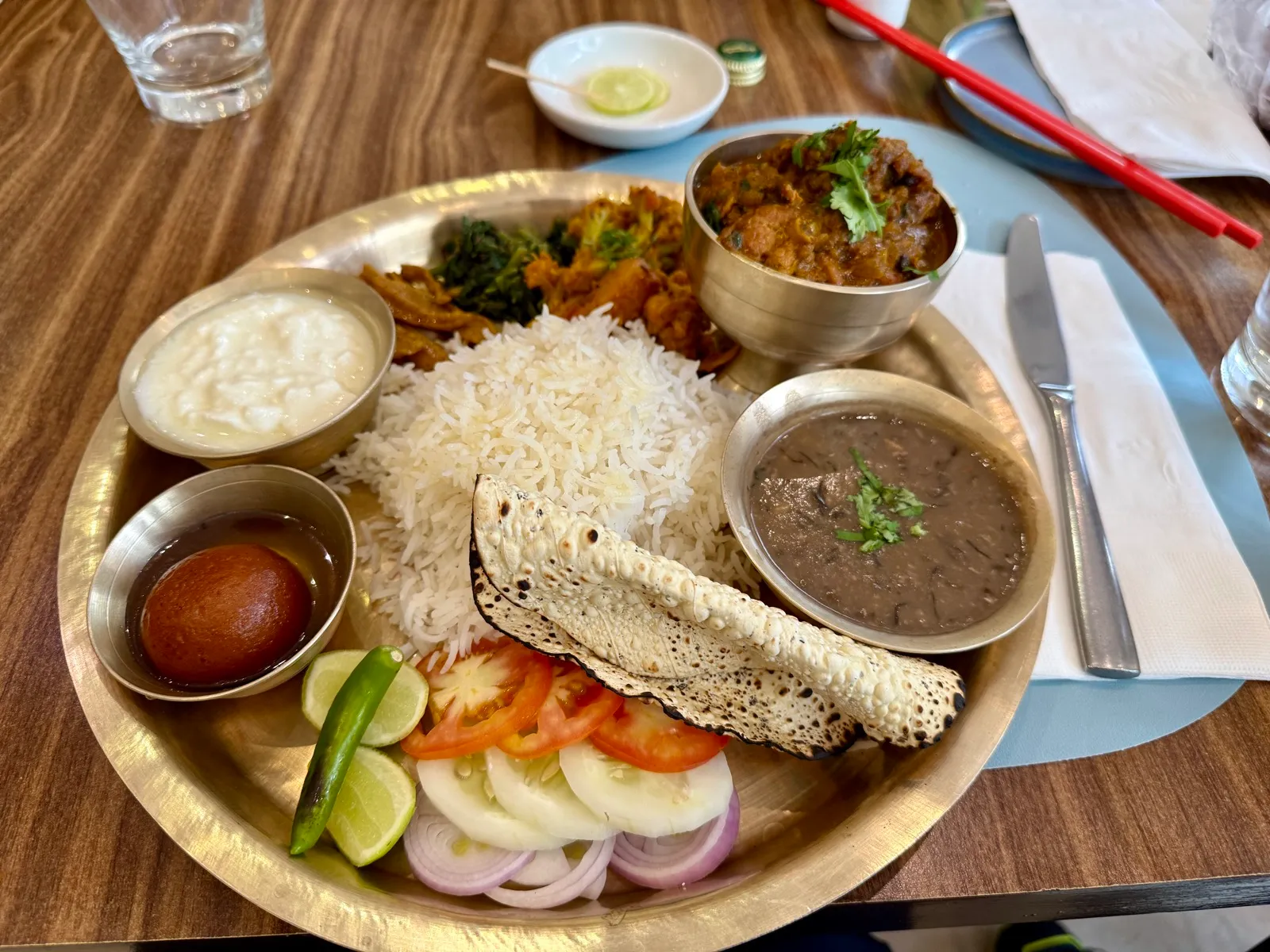金属餐盘里的 Dal Bhat 套餐，米饭、扁豆汤、咖喱鸡、酸奶、脆饼与蔬菜