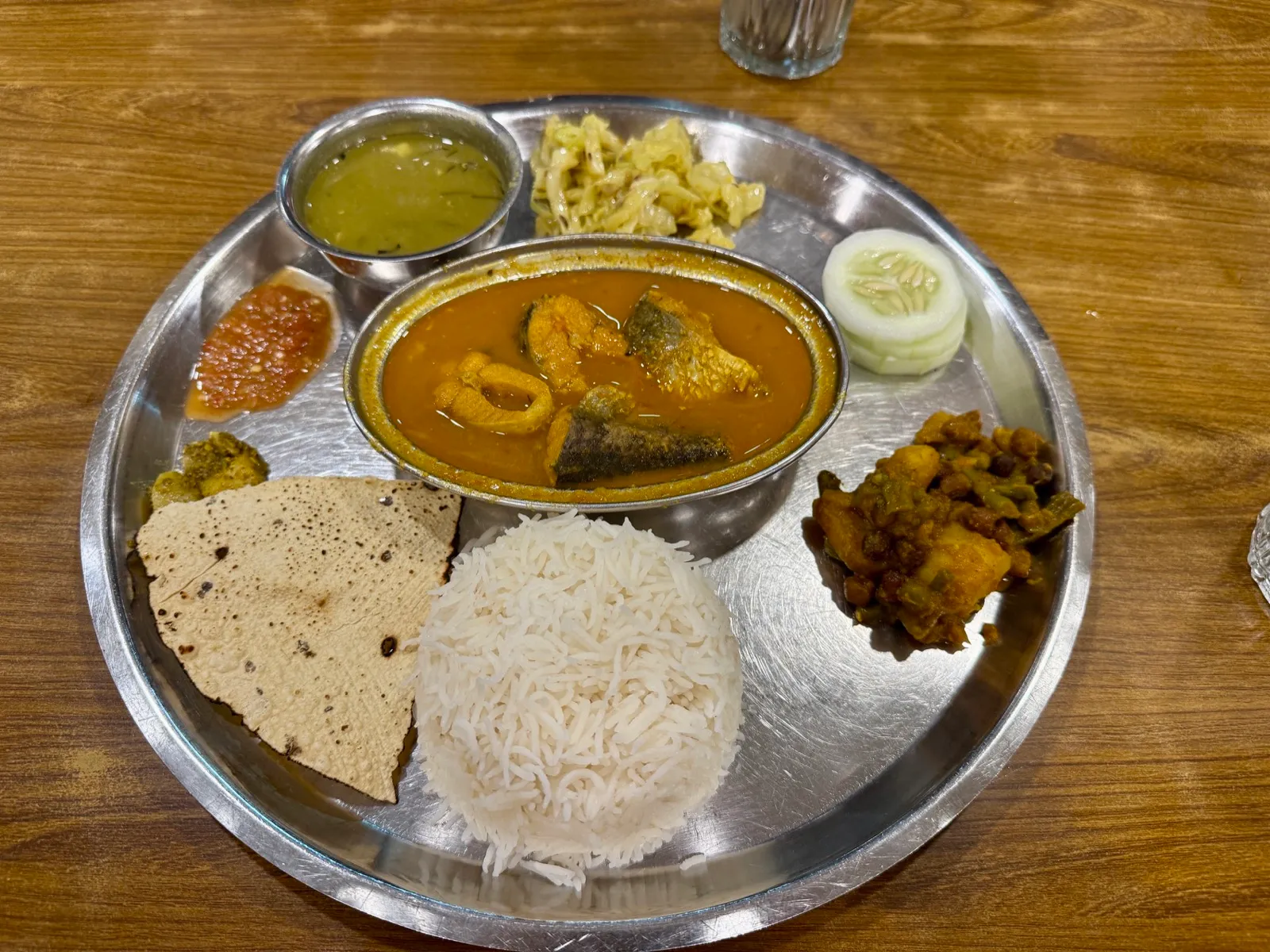 金属餐盘里的 Dal Bhat 套餐，中间是一份咖喱鱼，配米饭与脆饼