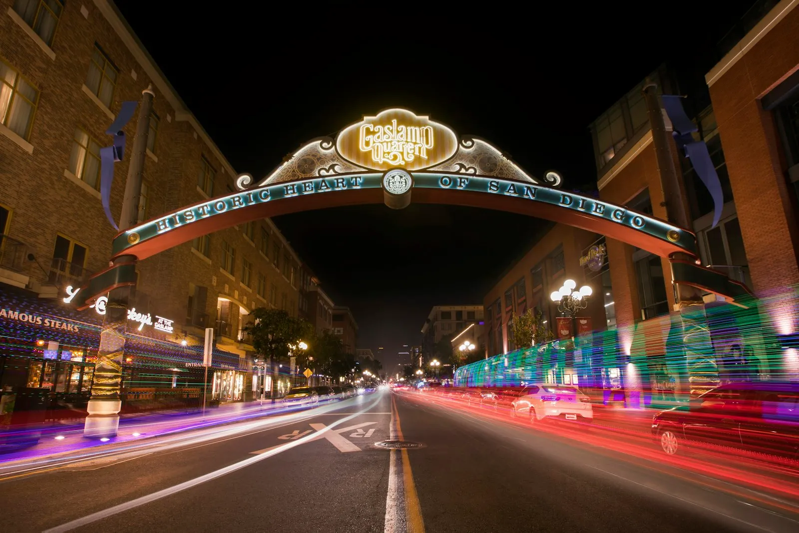 夜晚亮灯的 Gaslamp Quarter 拱门招牌横跨第五大道,车灯拉出红白光轨