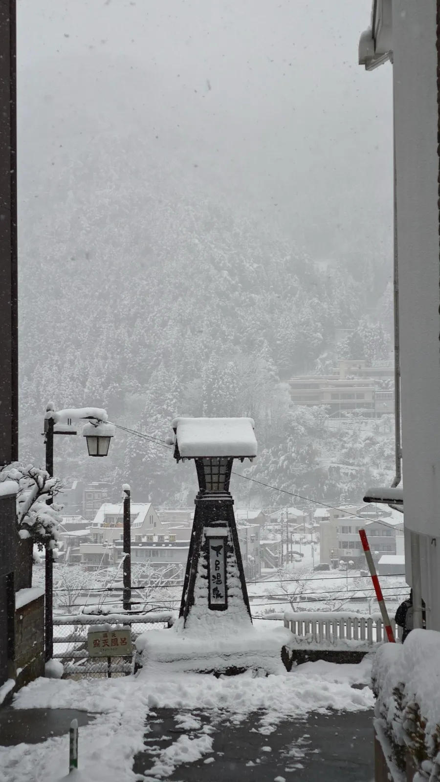 大雪中的下吕温泉街,石灯笼积着厚雪,山坡下是层叠的温泉旅馆