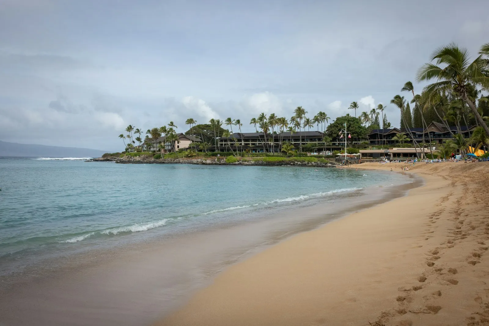 Napili Bay 弯月形的沙滩，浅绿海水，岸边是棕榈与低层度假村