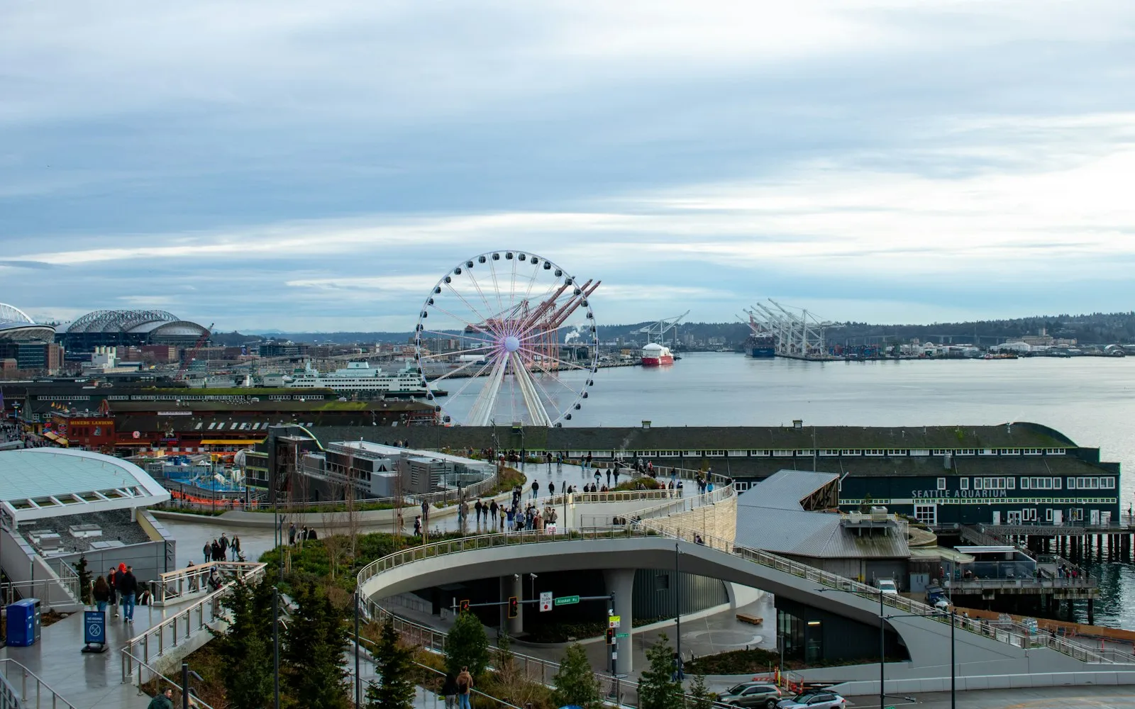 从 Overlook Walk 俯瞰西雅图新海滨，弧形坡道、Pier 62、水族馆与远处的摩天轮