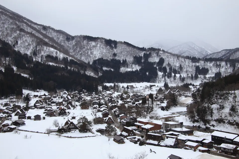 从高处俯瞰白川乡，雪覆盖的合掌屋村落散落在被白雪包裹的山谷之中