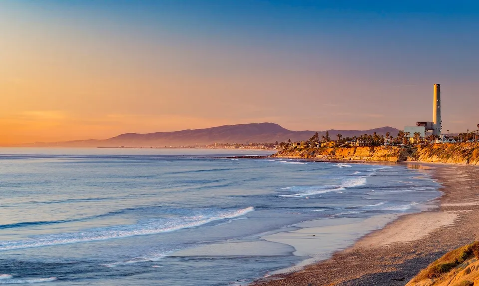 日落时分的 Carlsbad 到 Encinitas 海岸线,低矮海崖、浅滩与远处的山