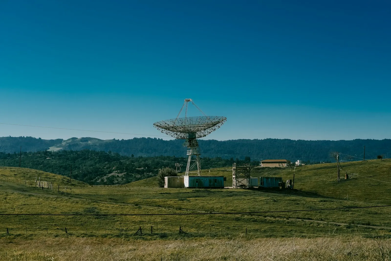 Stanford Dish 步道旁绿色山坡上的巨型射电天线,远处是树林与山脊