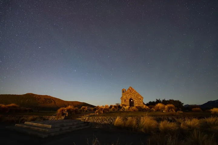 好牧羊人教堂夜景,石砌教堂被微光照亮,背后是漫天繁星