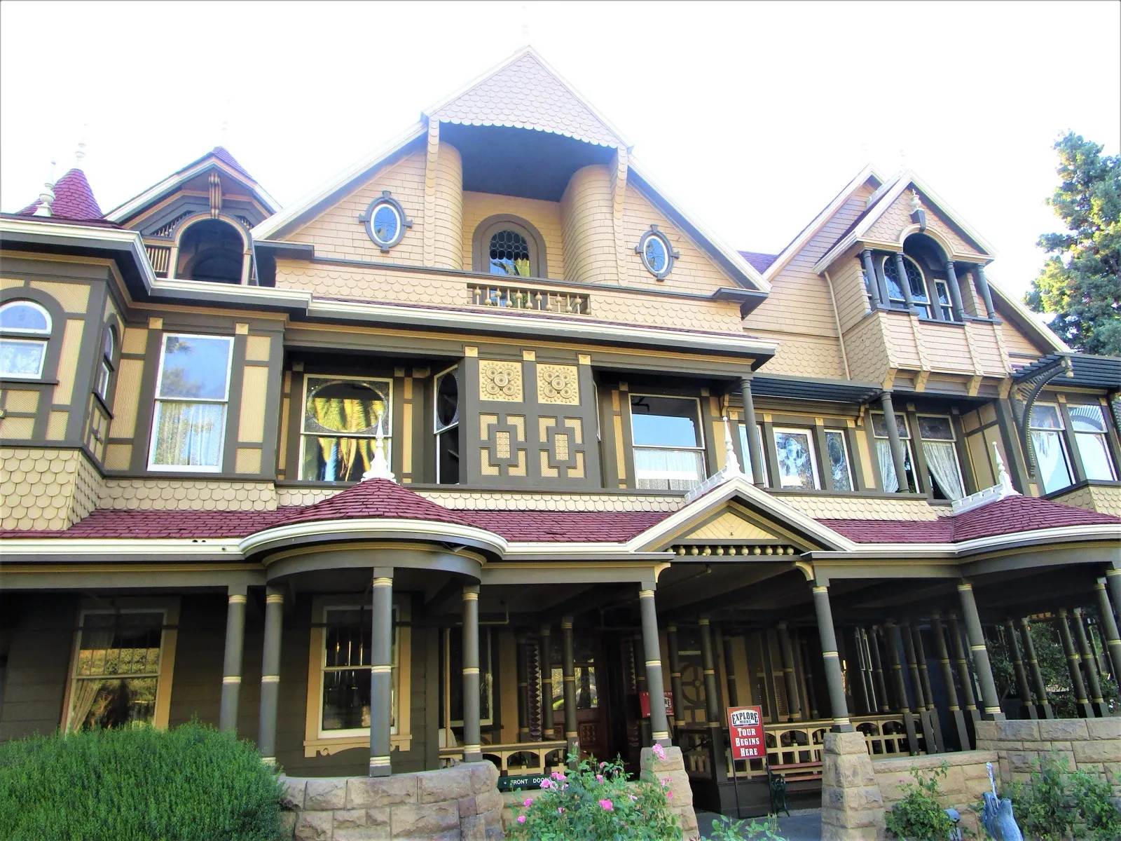 Winchester Mystery House 的正立面：黄褐色外墙、红色屋顶、三角山墙与前廊