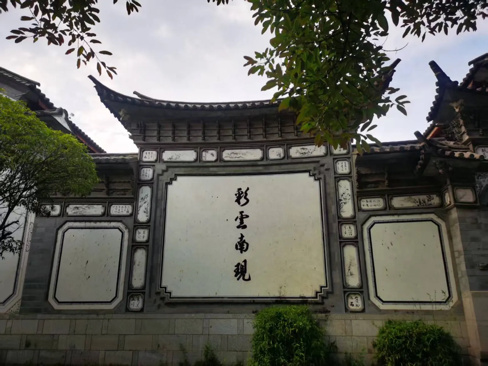 喜洲古镇白族民居的照壁，正中黑字写着「彩云南现」，四周是青砖与彩绘装饰