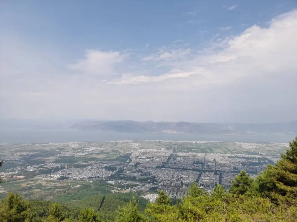 从苍山中和寺俯瞰大理坝子，苍翠山脚下城市铺展，远处是一线洱海与连绵青山