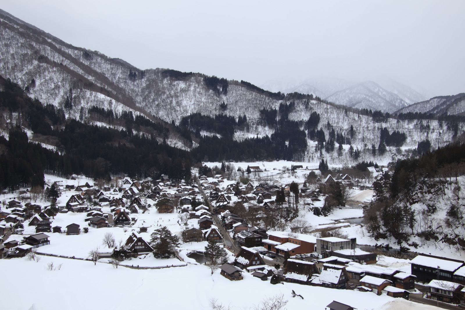 从高处俯瞰白川乡，雪覆盖的合掌屋村落散落在被白雪包裹的山谷之中
