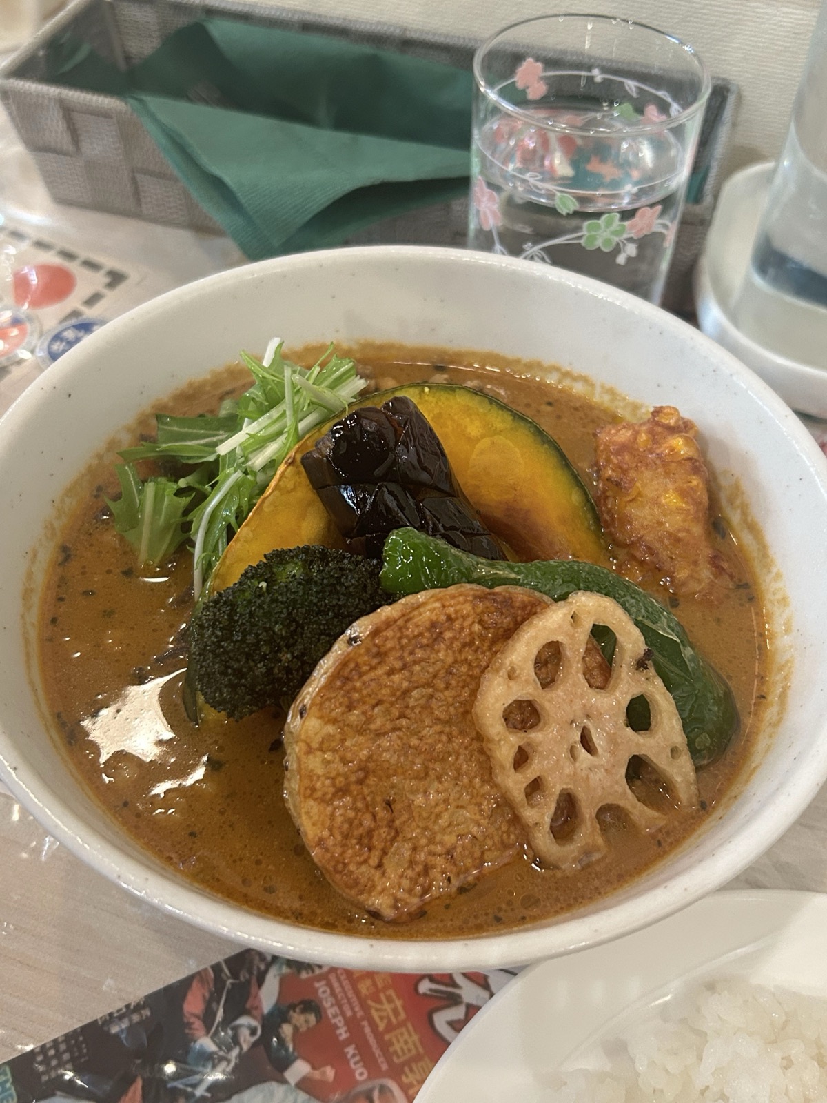 一碗浓稠的汤咖喱，里面有烤南瓜、莲藕、西兰花、茄子与炸鸡，旁边配着白米饭