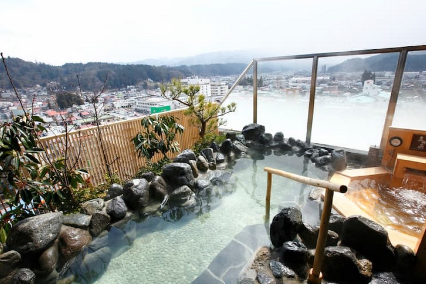 高山樱庵顶楼的露天石砌温泉池，越过木栅栏可以俯瞰高山小城与远山