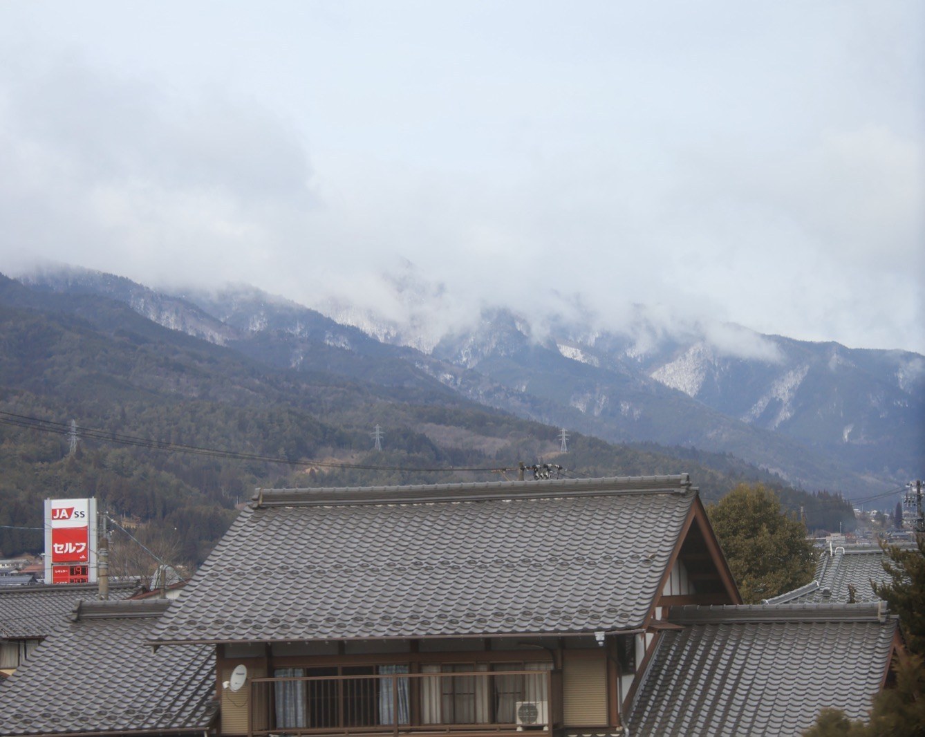 云雾缭绕的雪山下，几栋灰瓦传统民居错落排列