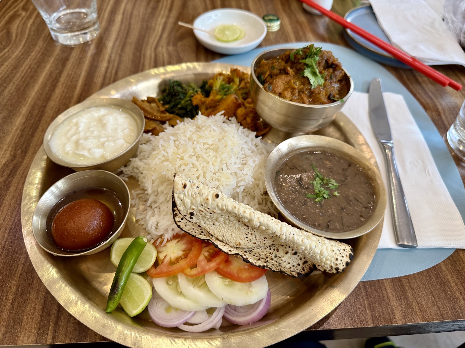 金属餐盘里的 Dal Bhat 套餐，米饭、扁豆汤、咖喱鸡、酸奶、脆饼与蔬菜