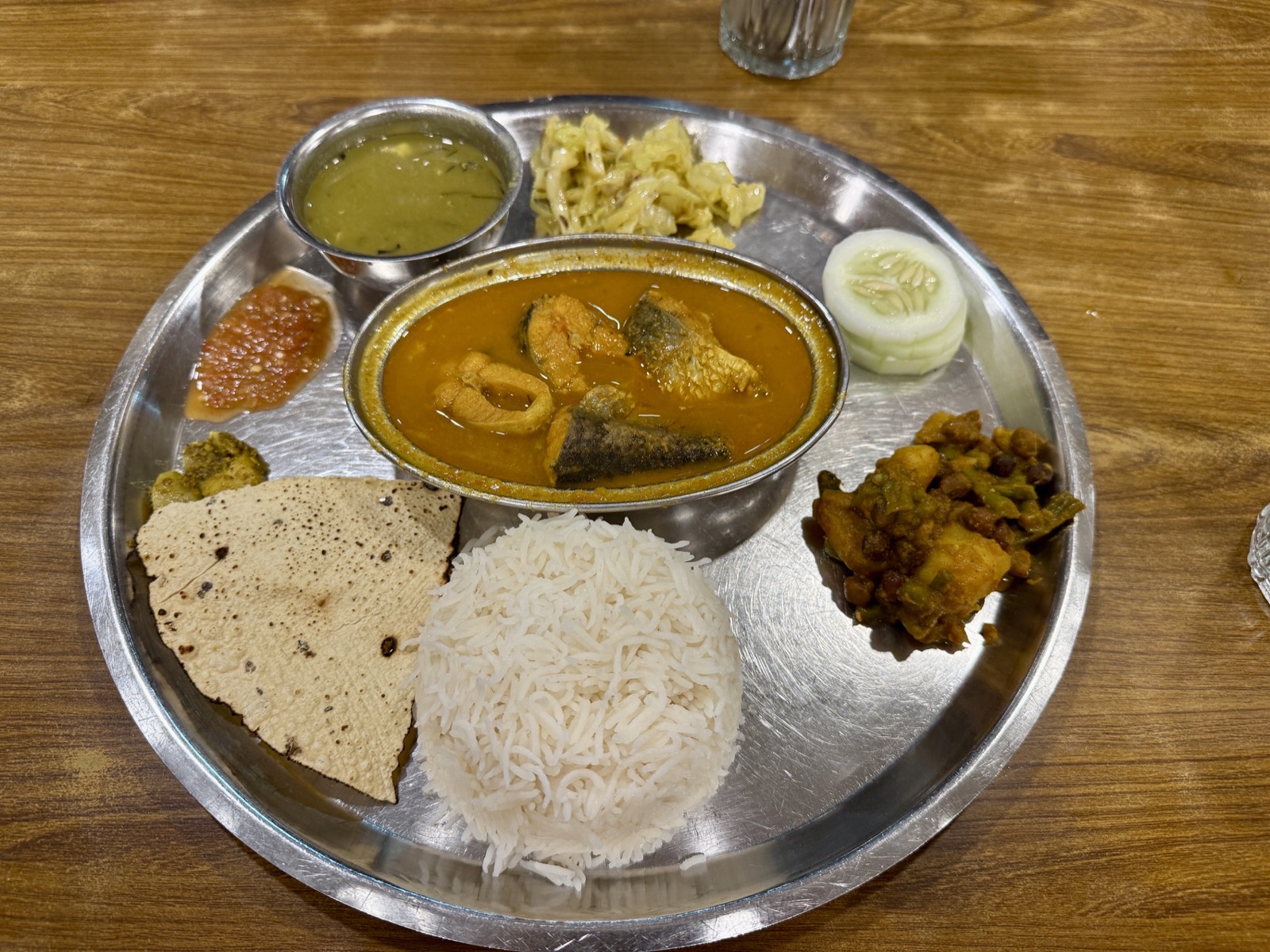 金属餐盘里的 Dal Bhat 套餐，中间是一份咖喱鱼，配米饭与脆饼