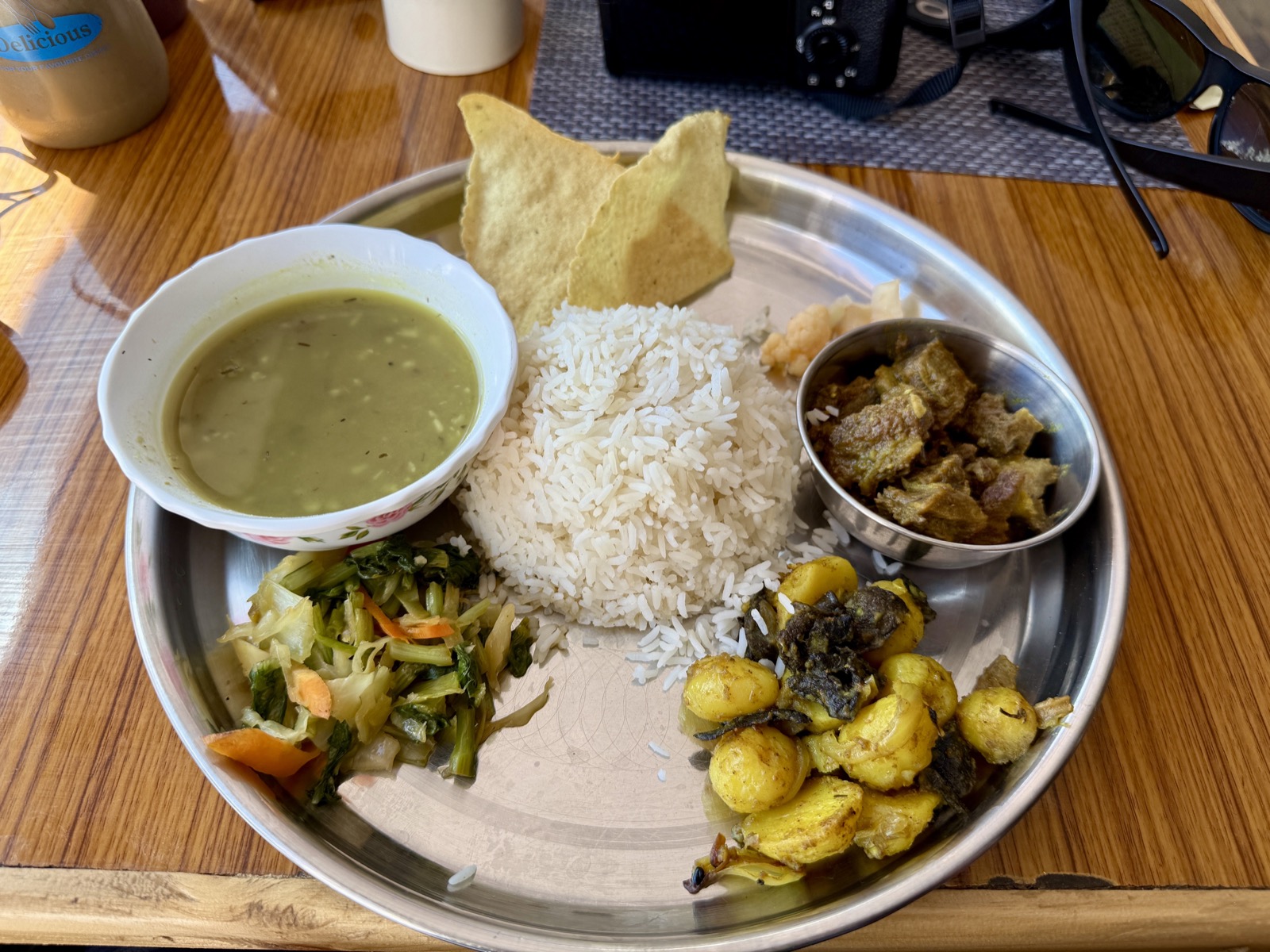 金属餐盘里的 Dal Bhat 套餐，配有炖牦牛肉、青菜与香料土豆