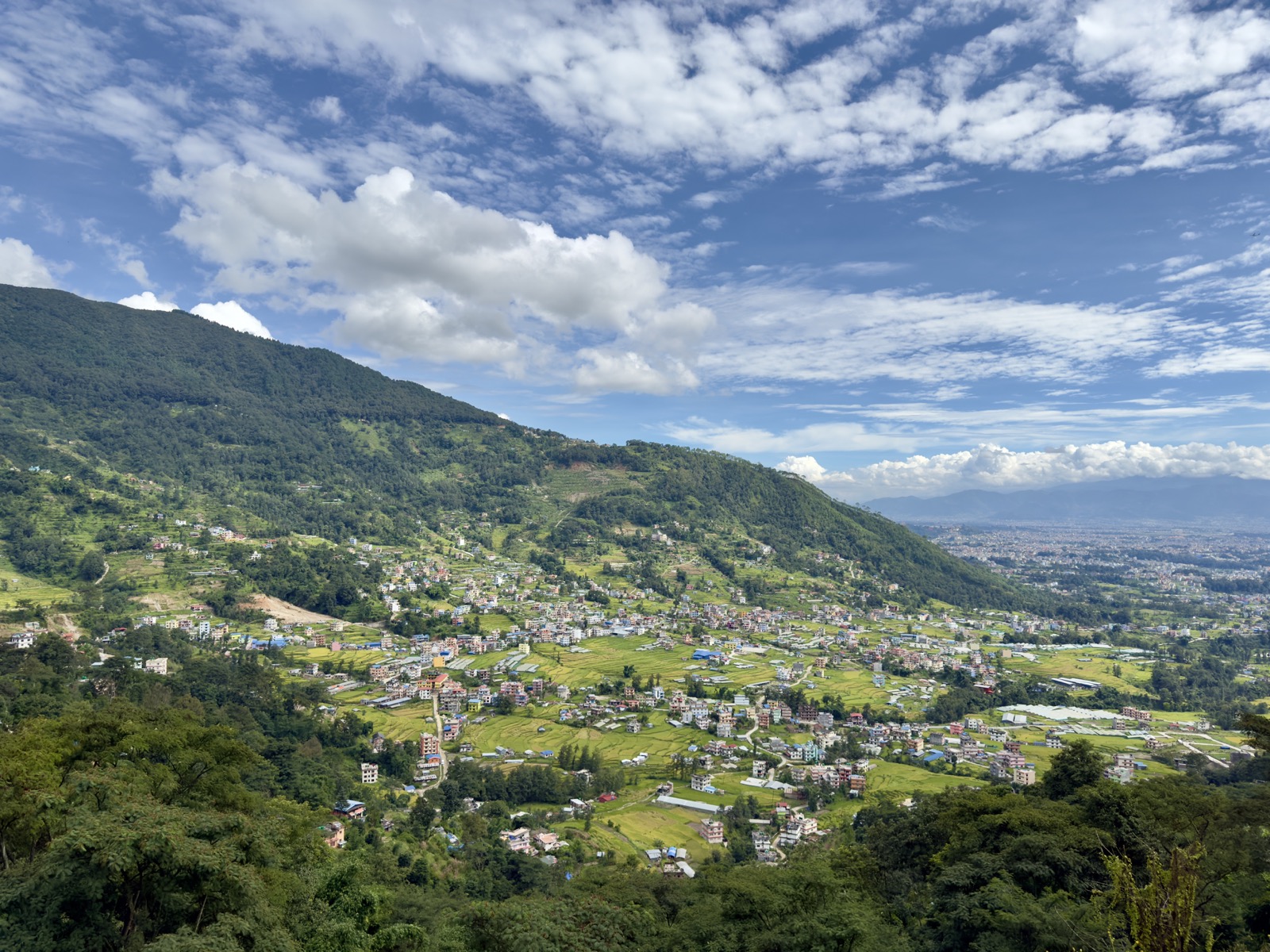 从山坡俯瞰加德满都谷地，绿色山峦间散布着密集的房屋与农田