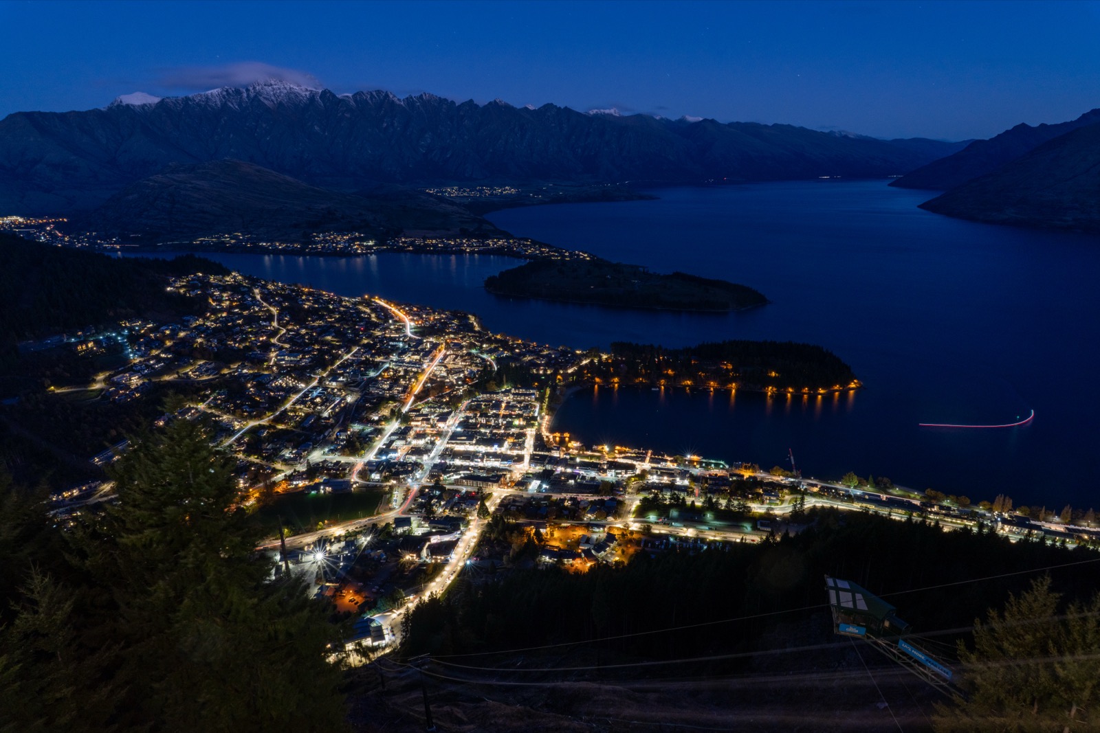 皇后镇夜景，灯火点点倒映在湖面，缆车轨道从山顶延伸而下