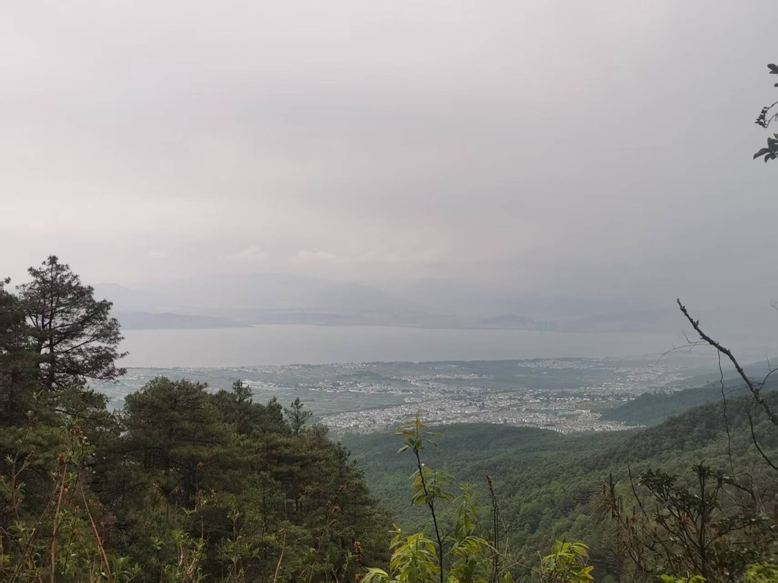 苍山玉带路上远眺，苍翠山林之下大理坝子铺展，远处一线洱海隐在薄雾里