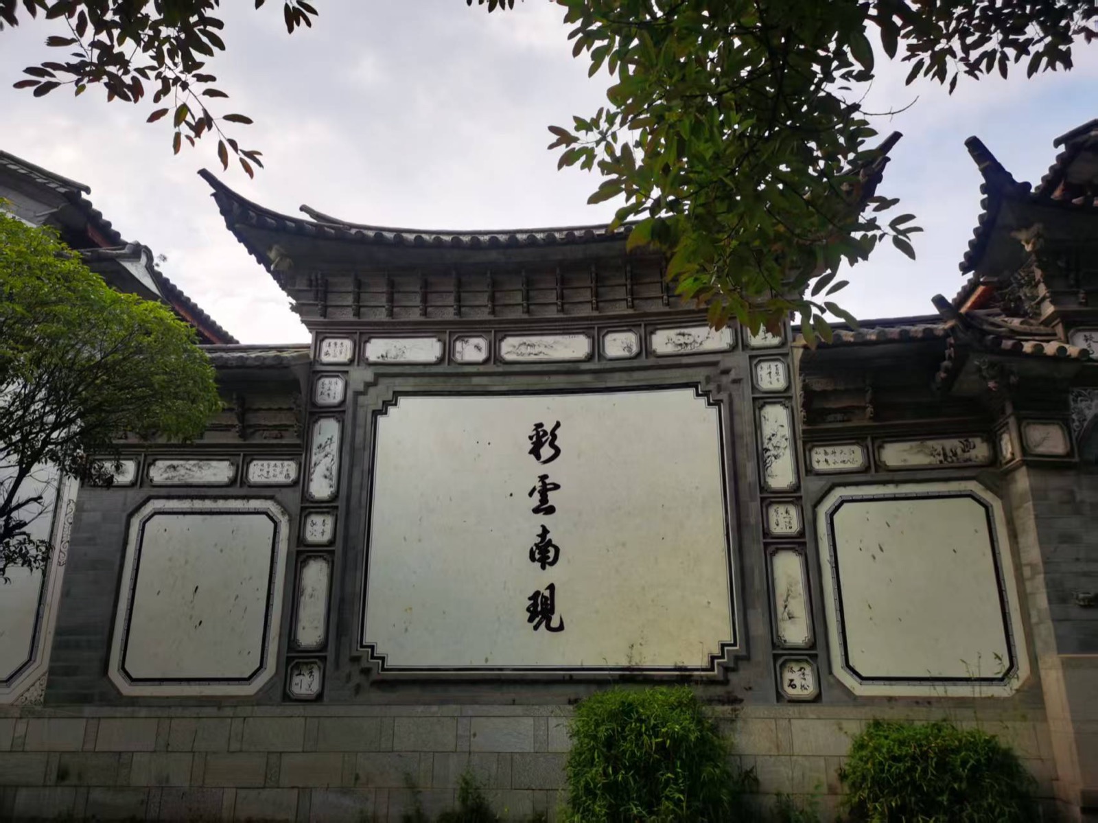 喜洲古镇白族民居的照壁，正中黑字写着「彩云南现」，四周是青砖与彩绘装饰