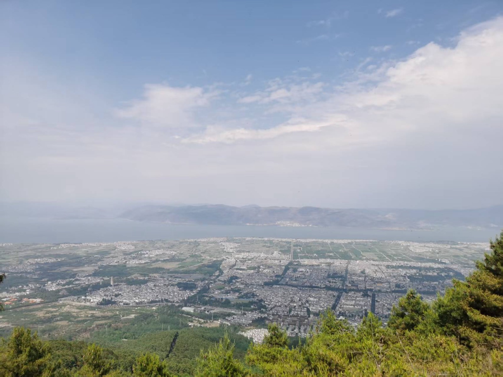 从苍山中和寺俯瞰大理坝子，苍翠山脚下城市铺展，远处是一线洱海与连绵青山